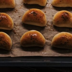 Golden brown dinner rolls fresh out of the oven on a baking sheet.