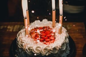 Celebrate with a festive strawberry-topped birthday cake adorned with sparkler candles, creating a joyful atmosphere.
