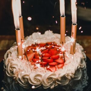Celebrate with a festive strawberry-topped birthday cake adorned with sparkler candles, creating a joyful atmosphere.