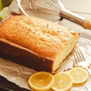 A scrumptious homemade lemon cake accompanied by fresh lemon slices, perfect for dessert lovers.