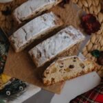 Sliced stollen bread and cappuccino on a festive winter table setting, evoking a warm holiday feel.