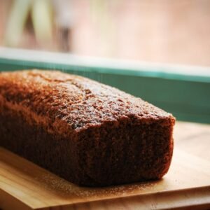 Closeup of sweet delicious fresh baked banana bread cake placed on wooden cutting board in kitchen