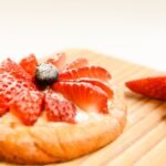 A delectable strawberry tart with a glossy finish on a wooden board, perfect for dessert lovers.